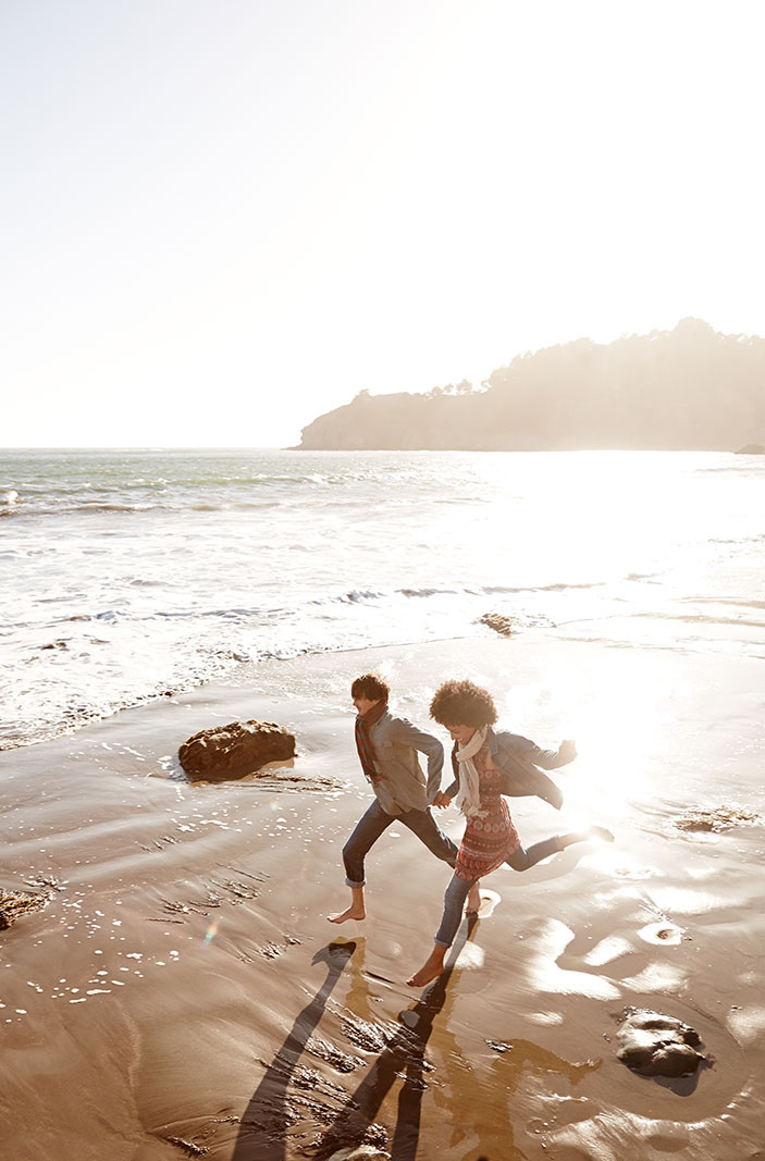 Young couple running on beach in CA  | Trinette+Chris Photographers